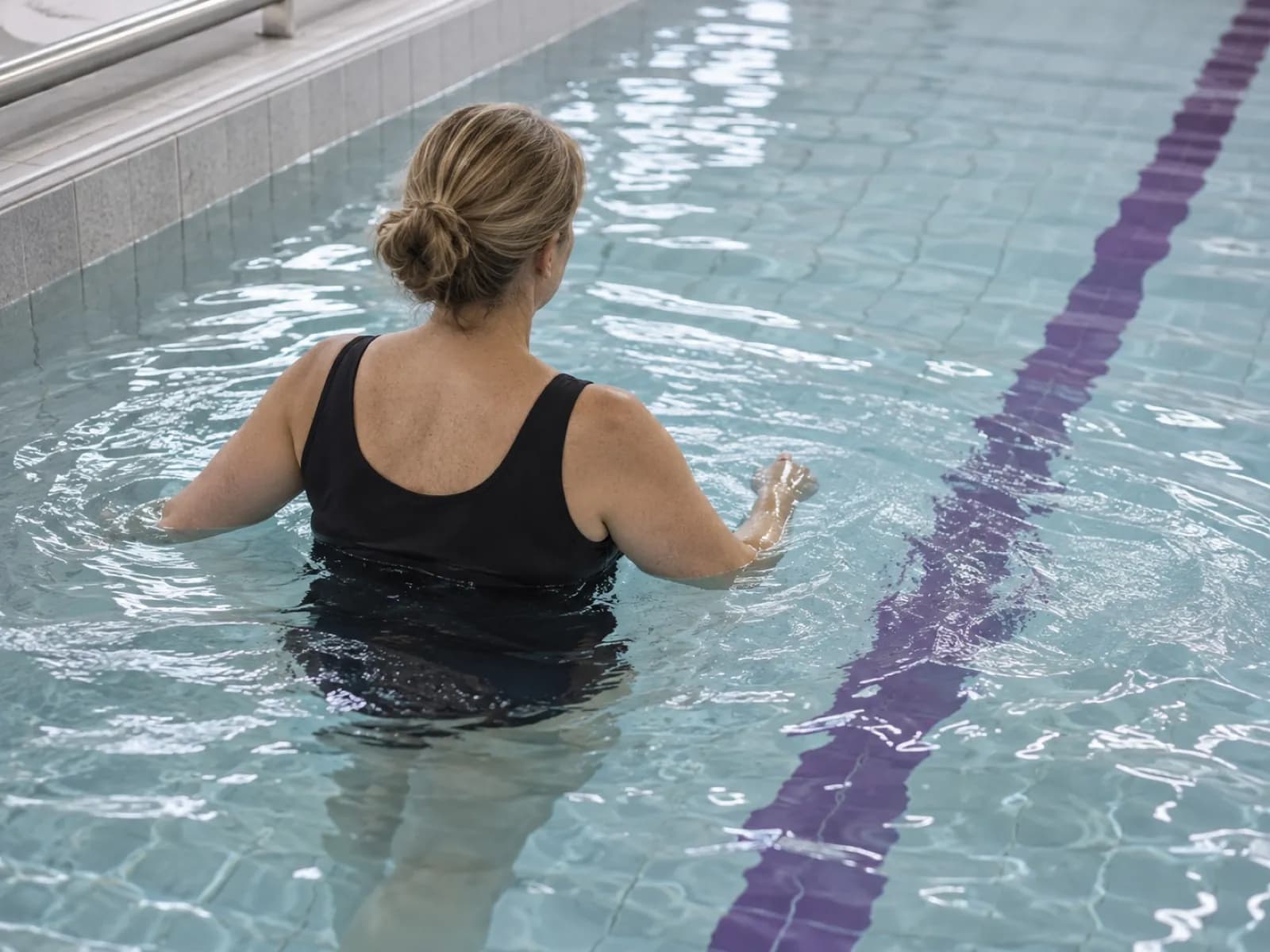 An adult walking in a hydrotherapy pool with the water at chest height